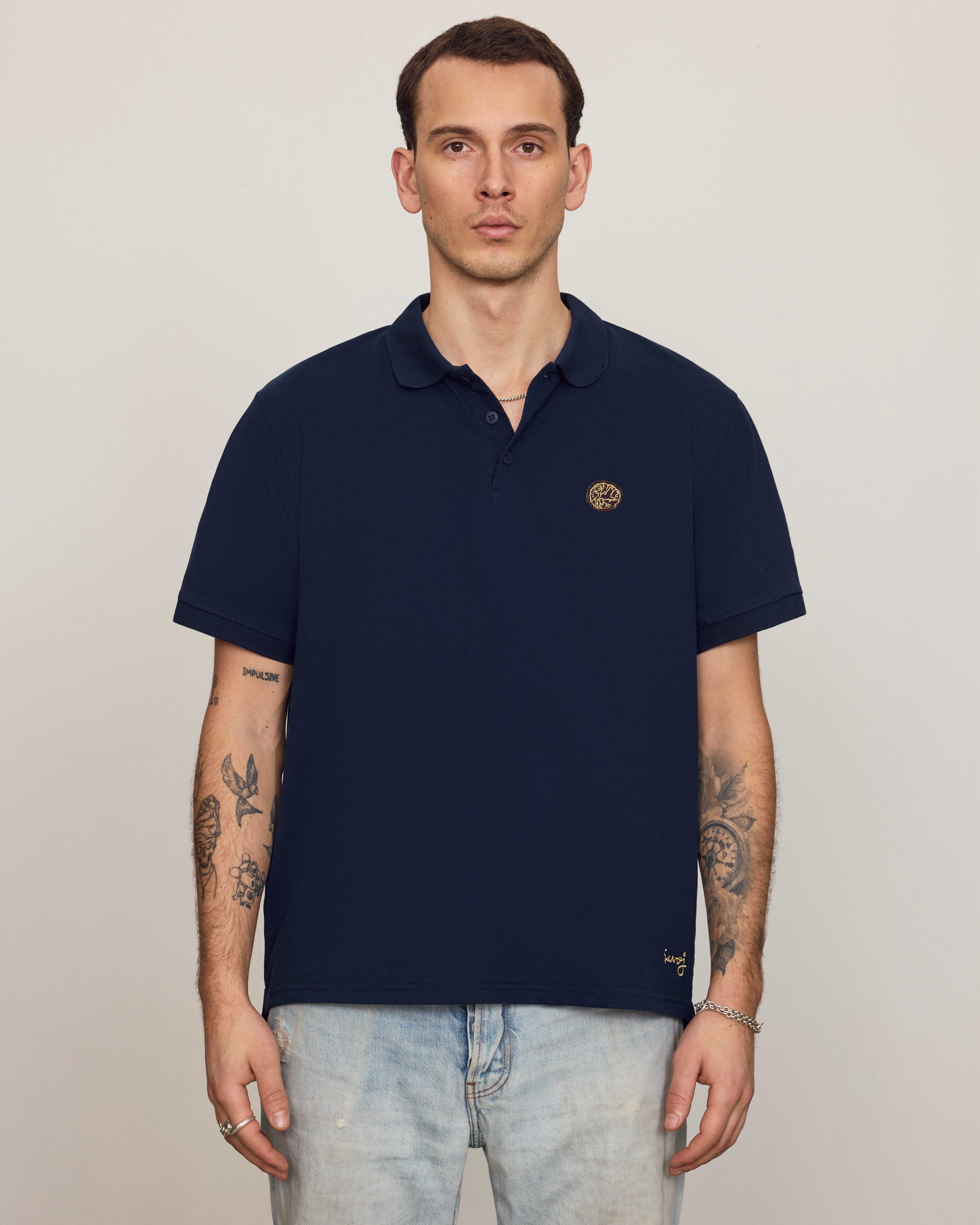 Male model wearing a deep navy piqué polo with Savoj knot emblem and signature embroidery.