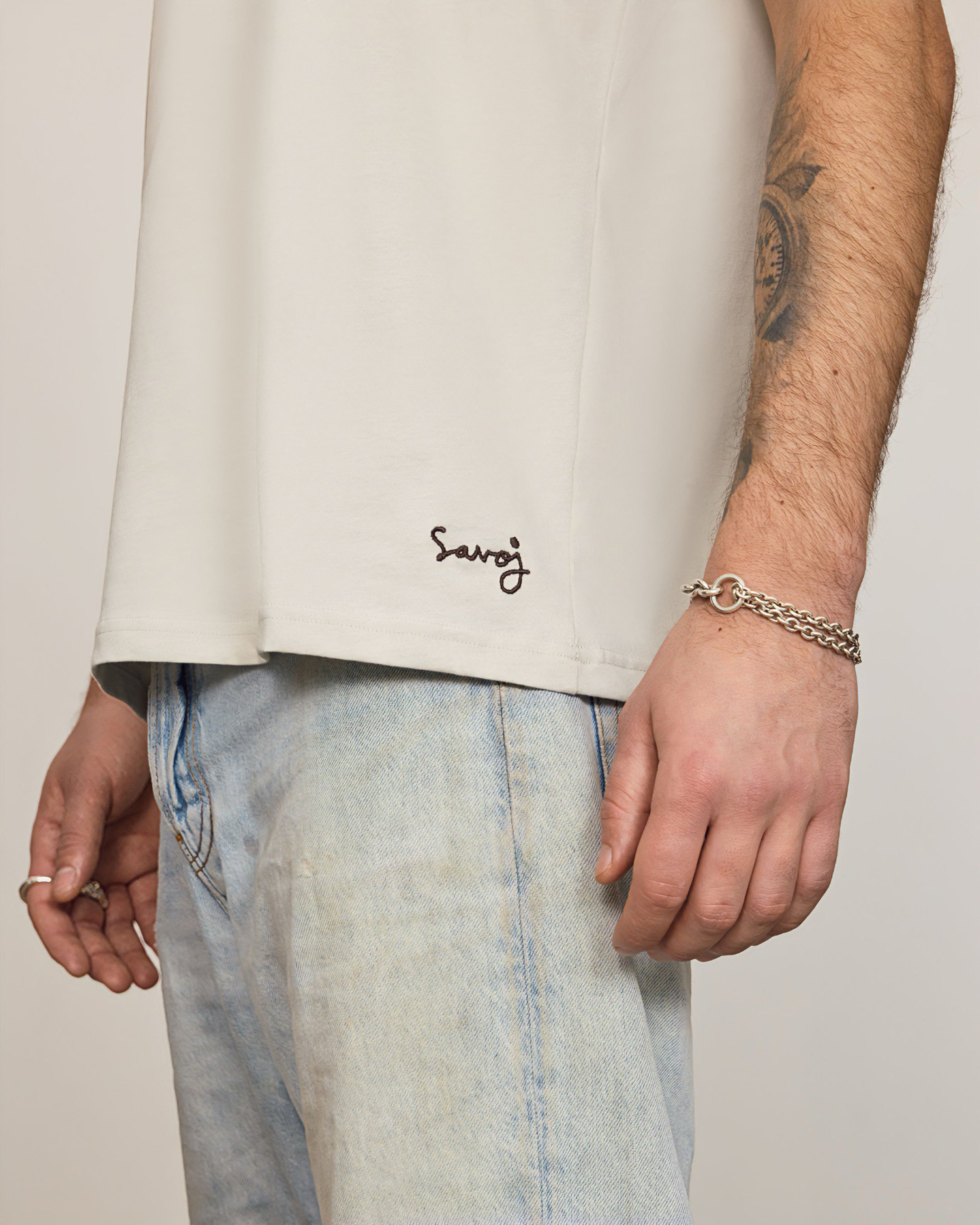 Male model wearing Unisex Savoj Egyptian Cotton Tee – Hem Embroidery Detail in Oatmilk White