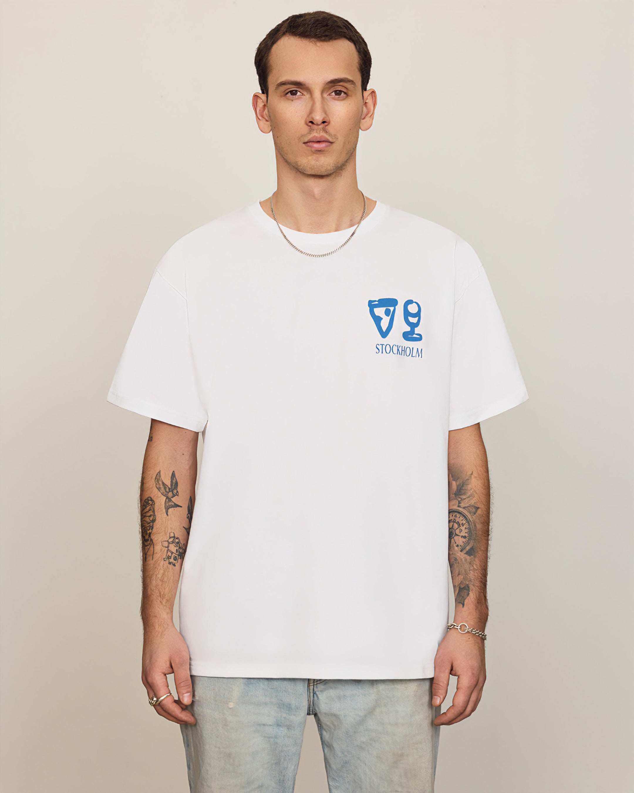 Model wearing a House of Savoj men's oversized white t-shirt with a Stockholm Pizzeria graphic on the front